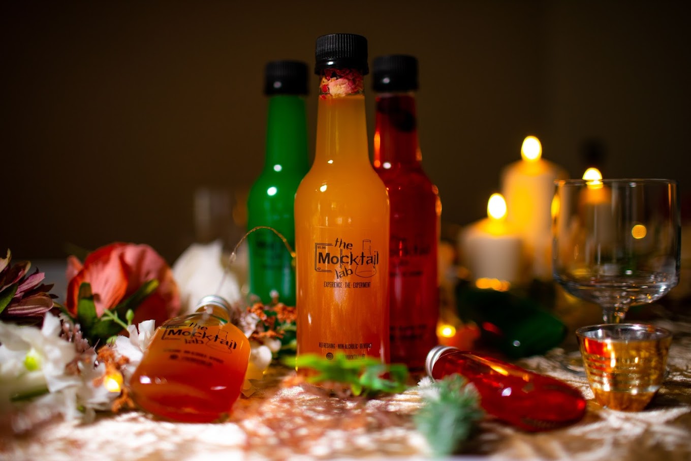 The Mocktail Lab bottled batch drinks glowing among candlelight and fresh flowers