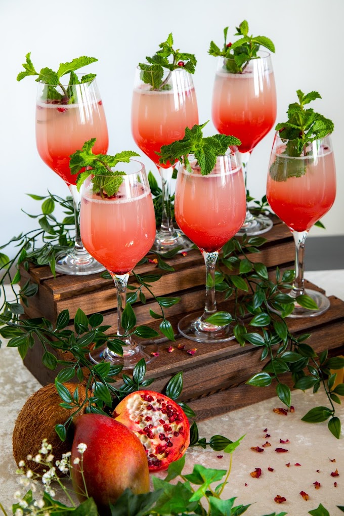 Pomegranate and mint mocktail served in wine glasses with fresh fruit